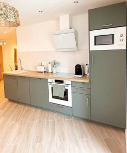 eine Küche mit grauen Schränken und weißen Geräten in der Unterkunft Appartement bord de mer « La Petite Ma-Line » in Cagnes-sur-Mer