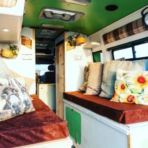 una cabaña con sofá y almohadas en Annie The Ambulance (Drive away campervan), en Skewen