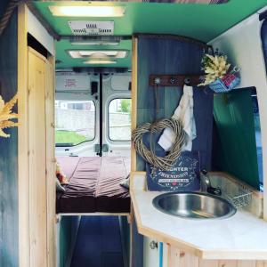 a bathroom with a sink and a bed in an rv at Annie The Ambulance (Drive away campervan) in Skewen