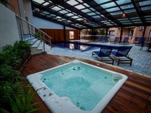 bañera de hidromasaje en una terraza junto a la piscina en Mais Incrível Apart no Wish Serrano en Gramado