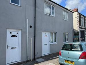 een auto geparkeerd voor een gebouw met twee witte deuren bij A spacious flat in Cardiff