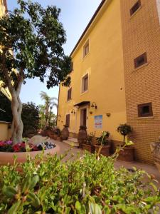 a building with a tree and plants in front of it at B&B Villa Colomba in Agrigento