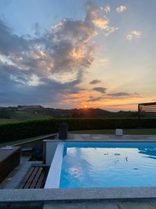a large swimming pool with a sunset in the background at Ca' del magu in San Michele Mondovì