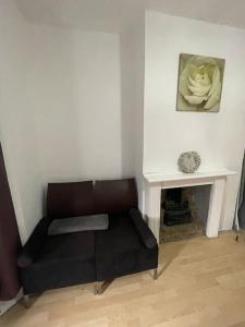 a black couch in a living room with a fireplace at Two Bedroom Maisonette in Erith in Dartford