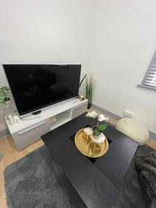a living room with a flat screen tv and a table at Two Bedroom Maisonette in Erith in Dartford