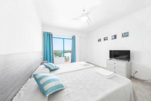 Biała sypialnia z 2 łóżkami i telewizorem w obiekcie Hostal Cala Llombards w mieście Cala Llombards