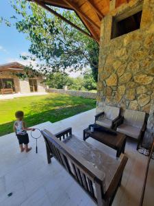 a little boy standing on a patio with benches at Orahovo stone vilas in Virpazar