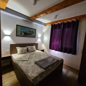 a bedroom with a bed with purple curtains at Orahovo stone vilas in Virpazar