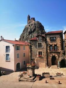 um edifício de pedra com uma montanha ao fundo em Au Bon Endroit em Aiguilhe