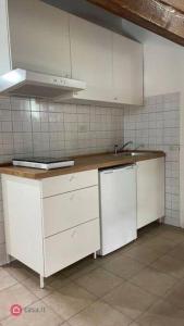 uma cozinha com armários brancos e um lavatório em Monolocale Oltretorrente em Parma