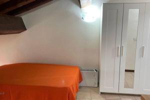 um quarto com uma cama laranja e um closet em Monolocale Oltretorrente em Parma