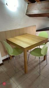 uma mesa de madeira e duas cadeiras verdes à sua volta em Monolocale Oltretorrente em Parma