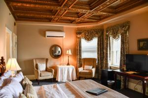 a bedroom with a bed and two chairs and a television at The Sayre Mansion in Bethlehem