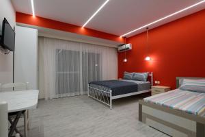 Schlafzimmer mit roten Wänden, einem Bett und einem Schreibtisch in der Unterkunft Vila SHAKAJ in Sarandë