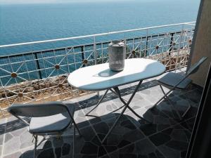 einen Tisch und zwei Stühle auf einem Balkon mit Blick auf das Wasser in der Unterkunft Vila SHAKAJ in Sarandë