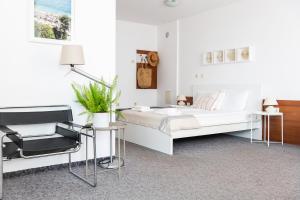 a white bedroom with a bed and a chair at Sea House Afrodita II in Nesebar