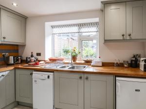 a kitchen with white cabinets and a sink and a window at 76 High Street in Redcar