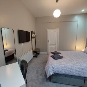 a bedroom with a bed and a table and a television at Woodstock Townhouse Belfast in Belfast