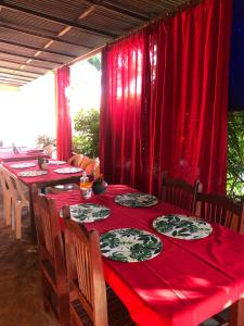 uma sala de jantar com mesas vermelhas e cadeiras com cortinas vermelhas em Pousada Chácara do Coqueiro em Barreirinhas
