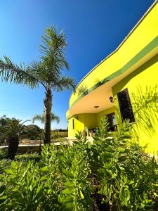 ein gelbes Gebäude mit einer Palme davor in der Unterkunft Mondoverde Apartments & Rooms in Surano