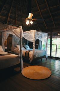 two beds in a room with a fan and a rug at Bluebayou Bacalar in Bacalar