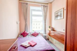 Schlafzimmer mit einem Bett mit rosa Bettwäsche und einem Fenster in der Unterkunft WonderHostel on Nevsky 23 in Sankt Petersburg