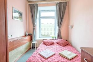 1 dormitorio con cama rosa y ventana en WonderHostel on Nevsky 23, en San Petersburgo