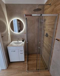 a bathroom with a shower and a sink and a mirror at Apartamenty Malaga II in Darłowo