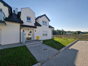 una gran casa blanca con entrada y césped en Apartamenty Malaga II, en Darłowo