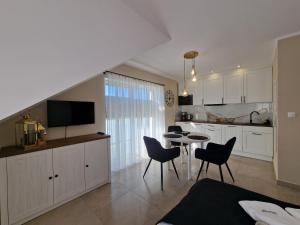 a kitchen and dining room with a table and chairs at Apartamenty Malaga II in Darłowo