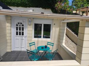 un patio con 2 sillas, una mesa y una puerta en Magnifique maison Dans un village du Vexin, en Ableiges