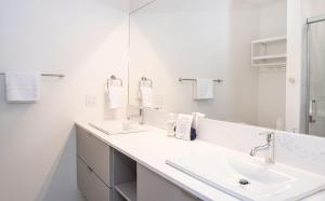 a white bathroom with two sinks and a mirror at Cabot Views by Revelstoke Vacations in Revelstoke +20 photos