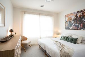 a white bedroom with a large bed and a desk at Cabot Views by Revelstoke Vacations in Revelstoke