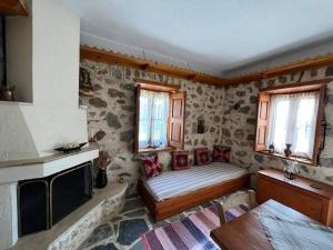a room with a bed and a fireplace and windows at Calliope stone house in Emborios