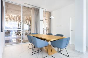 a dining room with a wooden table and blue chairs at Crystal I Luxury Apartments by EnjoyaHome in Santiago del Teide
