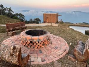 a brick fire pit on a hill next to a lake at Chalés de luxo na Serra Catarinense - VST in Annitapolis