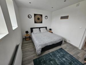 sypialnia z łóżkiem z białymi ścianami i drewnianą podłogą w obiekcie charmant appartement confort déco neuf , proche Epinal et Lac de Bouzey w mieście Uxegney