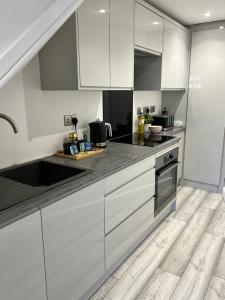 a kitchen with white cabinets and black counter tops at The Wedge in Southend-on-Sea