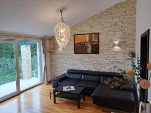 a living room with a black couch and a brick wall at Apartments Villa Sotlar with pool in Umag