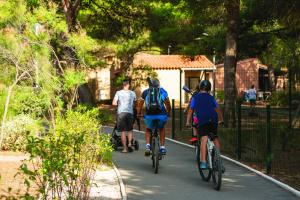a group of people riding bikes down a path at SOWELL HÔTELS Les Jardins du Cap in Cap d'Agde