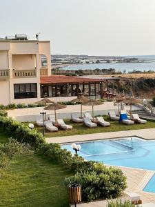 a resort with a swimming pool with chairs and umbrellas at Panorama Hotel in Falasarna