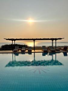 a swimming pool with chairs and the ocean in the background at Panorama Hotel in Falasarna