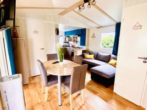 una cucina e un soggiorno con tavolo e divano di Évasion océanique : Mobil-home dans un camping 4* à 50m de l'océan a La Bétaudière