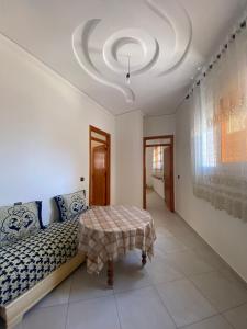 Schlafzimmer mit einem Bett und einer Decke mit einem Tisch in der Unterkunft Appartement proche de la corniche in Al Hoceïma