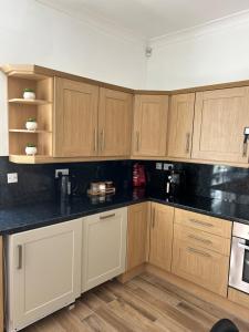 a kitchen with wooden cabinets and black counter tops at 1L Albert Place in Polmont