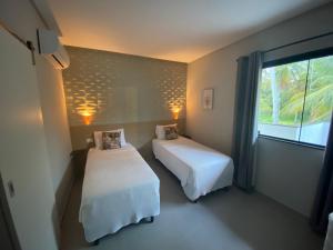 um quarto de hotel com duas camas e uma janela em Mar e Lar em Maragogi