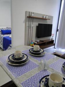 a table with plates and cups on top of it at SUNNY HALL in Porto De Galinhas