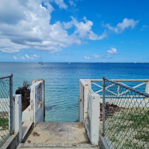 an open gate to the ocean with a boat in the water at Pierre's Place Grand-Case in Grand Case