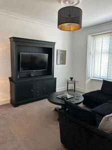 a living room with a couch and a flat screen tv at 1L Albert Place in Polmont