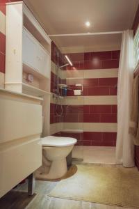 a bathroom with a toilet and a red wall at Pierre's Place Grand-Case in Grand Case